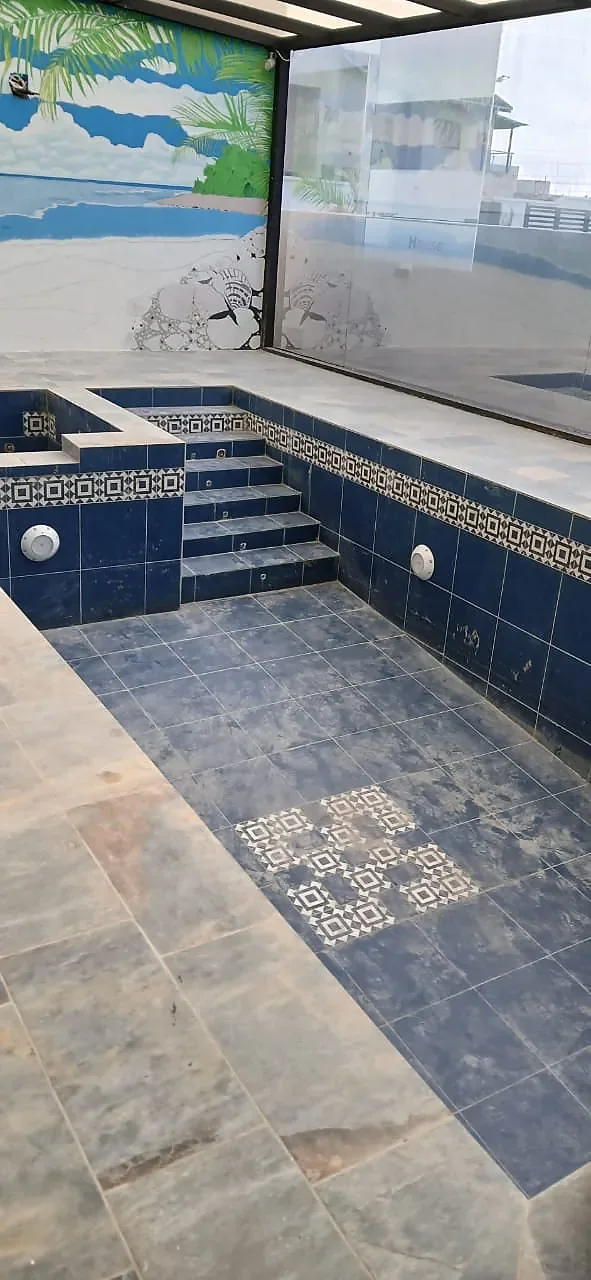 The same pool in daylight, tiled in deep blue with a patterned border and tiled steps.