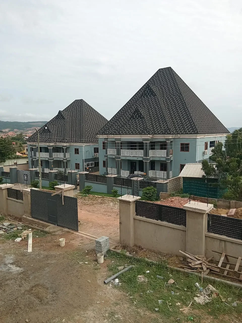 Two matching two-storey blocks finished and painted, with balconies, a boundary wall and planted grounds.